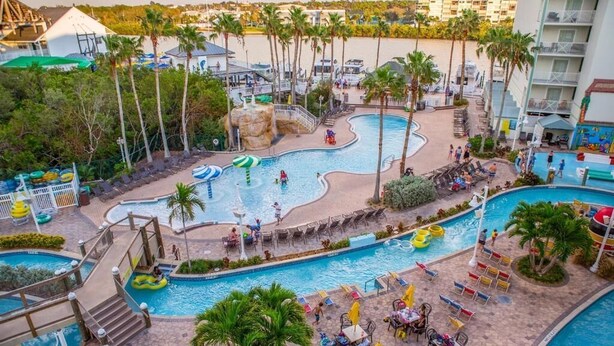 Un resort con varias piscinas, palmeras y zonas de estar al aire libre.
