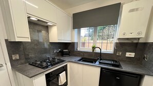 Une cuisine moderne avec des meubles blancs, une cuisinière noire, un lave-vaisselle noir et une fenêtre donnant sur l’extérieur.