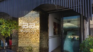 A modern building entrance with a textured wall and a glass door. - 22 Hostel (Chiang Mai)
