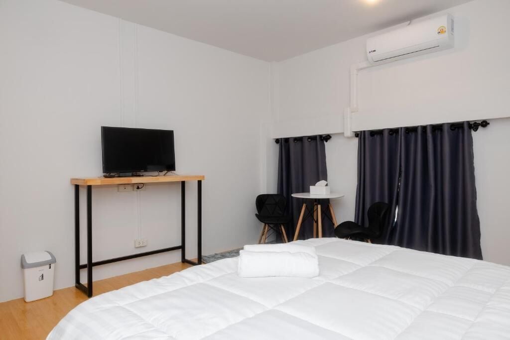 Habitación de hotel con cama, escritorio con televisor, una mesita y una silla.