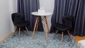 A room with a round table and two black chairs with wooden legs. - 22 Hostel (Chiang Mai)
