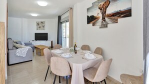 Un saló modern amb un sofà, televisió i zona de menjador preparada per a dinar.