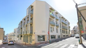 Un edifici residencial de diversos pisos amb balcons i entrada al nivell del carrer.