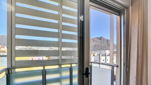 Un balcó amb vista a un paisatge de muntanyes i edificis urbans.