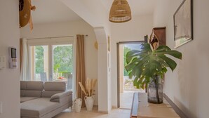 Una sala moderna con un sofá gris, una planta grande en maceta y una lámpara colgante de mimbre.