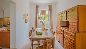Un comedor con una mesa y sillas de madera, una cocina con armarios de madera y un ventanal con cortinas.