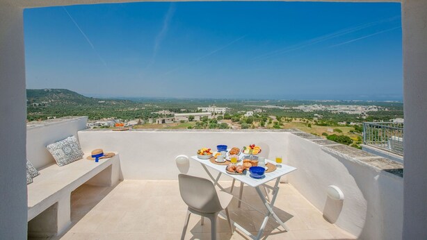 Un balcon avec une table préparée pour le petit-déjeuner, offrant une vue sur un paysage magnifique.