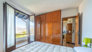 Un dormitorio con una cama grande, un armario de madera y vistas al exterior.