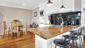 A modern kitchen with a wooden island, bar stools, and pendant lighting.
