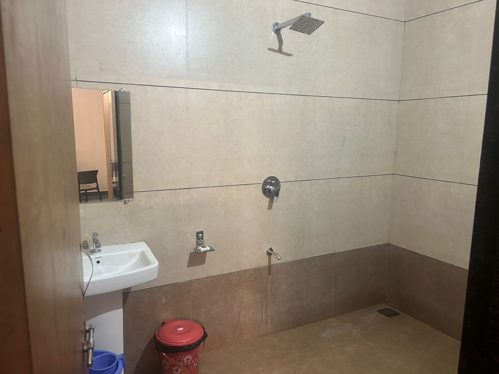 A small, tiled bathroom with a shower, a sink, and a mirror.