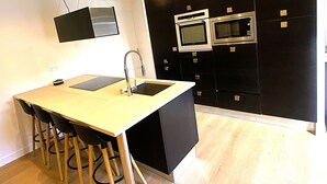 A modern kitchen with a central island, black cabinets, and stainless steel appliances. - L'instant d'un souvenir Gite 10 people 135 m² - 4 bedrooms - 7 beds - 2 bathrooms (Taupont)