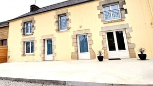 A two-story building with multiple windows, a balcony, and a door. - L'instant d'un souvenir Gite 10 people 135 m² - 4 bedrooms - 7 beds - 2 bathrooms (Taupont)