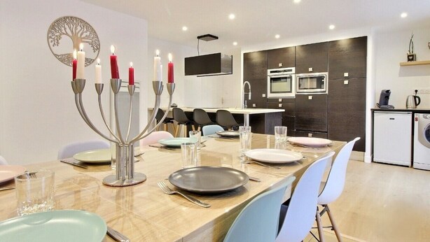 A modern dining area with a long table set for six, surrounded by chairs. - L'instant d'un souvenir Gite 10 people 135 m² - 4 bedrooms - 7 beds - 2 bathrooms (Taupont)