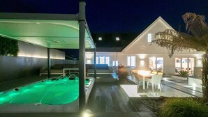 A modern house with a swimming pool, outdoor seating, and a well-lit patio area. - Solstice, Carbis Bay – Sleeps 8 – Sea Views – Luxury Hot Tub – On-Site Parking (Carbis Bay)