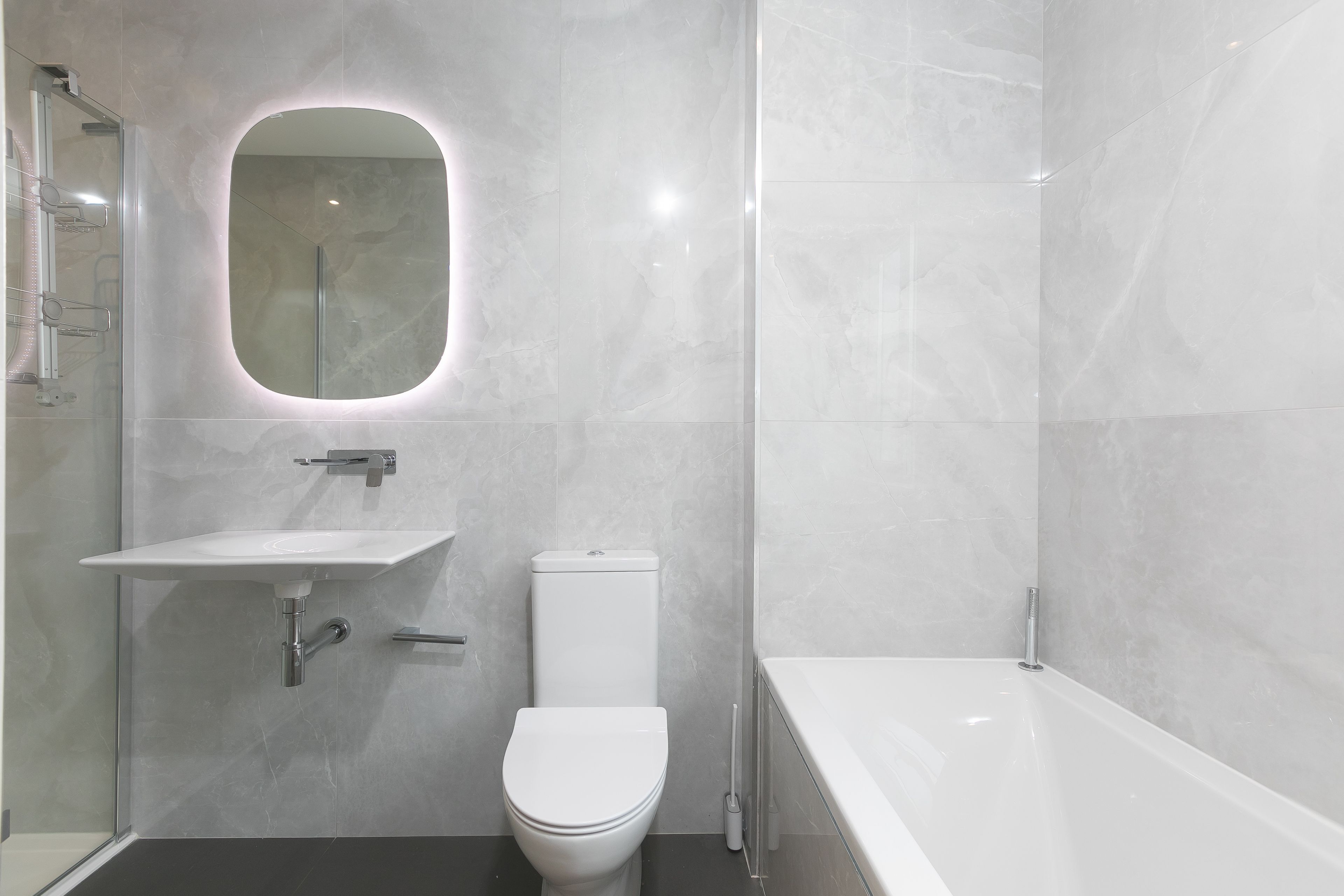 Une salle de bain moderne avec des toilettes blanches, un lavabo et une baignoire.