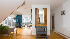 A modern living room with a wooden coffee table, a sofa, and a dining area with a table and chairs. - Solstice, Carbis Bay – Sleeps 8 – Sea Views – Luxury Hot Tub – On-Site Parking (Carbis Bay)