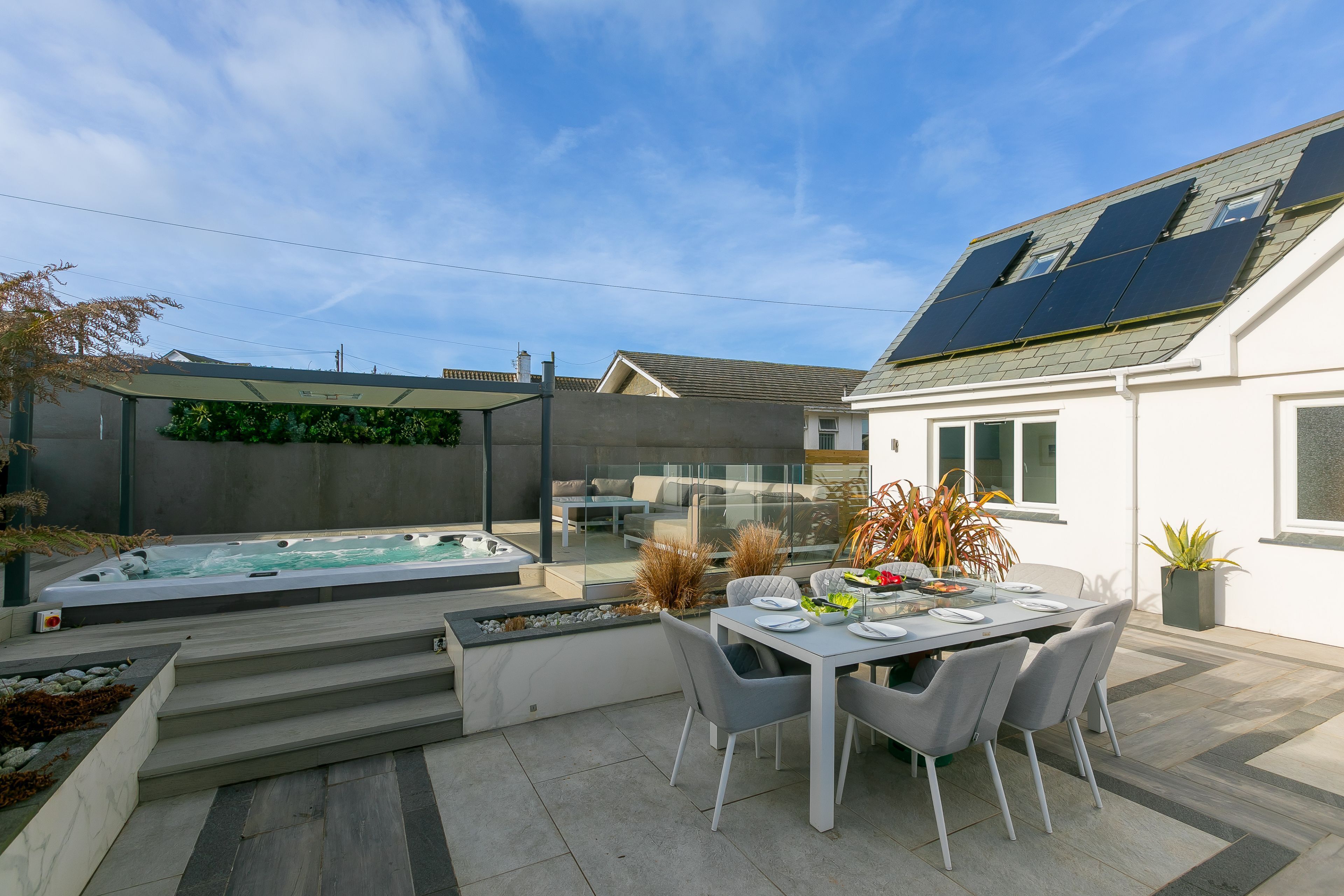 Une terrasse extérieure moderne, dotée d’un jacuzzi, d’une table à manger et de chaises.