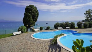 A swimming pool with a view of the sea, a bench, and a tree. - Specchio sul Lago in Manerba del Garda (Manerba del Garda)