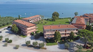 A coastal hotel with multiple buildings, a parking area, and a view of the sea. - Specchio sul Lago in Manerba del Garda (Manerba del Garda)