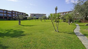 A courtyard with a pathway, surrounded by buildings with multiple windows and balconies. - Specchio sul Lago in Manerba del Garda (Manerba del Garda)