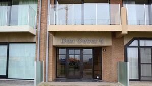 Un edificio con un letrero que dice "Den Oever 4" y una entrada por puerta de cristal.