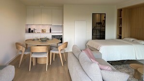 Un espacio habitable moderno y funcional con comedor, kitchenette y un dormitorio.