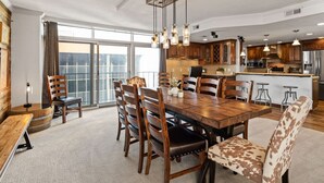 Un vaste espace dédié à la salle à manger, avec une grande table en bois, de nombreuses chaises et un coin bar équipé de tabourets.