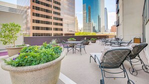 Une terrasse sur le toit, aménagée avec des espaces pour s’asseoir à l’extérieur, des plantes en pot et offrant une vue sur le paysage urbain.