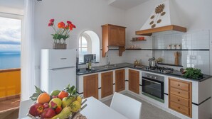 A modern kitchen with white cabinets, wooden accents, and a view of the sea through an open window. - Romantic cottage with outdoor heated whirlpool and breathtaking views (Praiano)