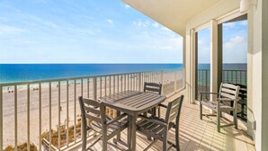 Ein Balkon mit Tisch und Stühlen mit Blick auf einen Strand.
