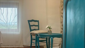 A teal chair with a cushion and a small table with a vase of flowers. - Vercors en vert (Saint-Romans)