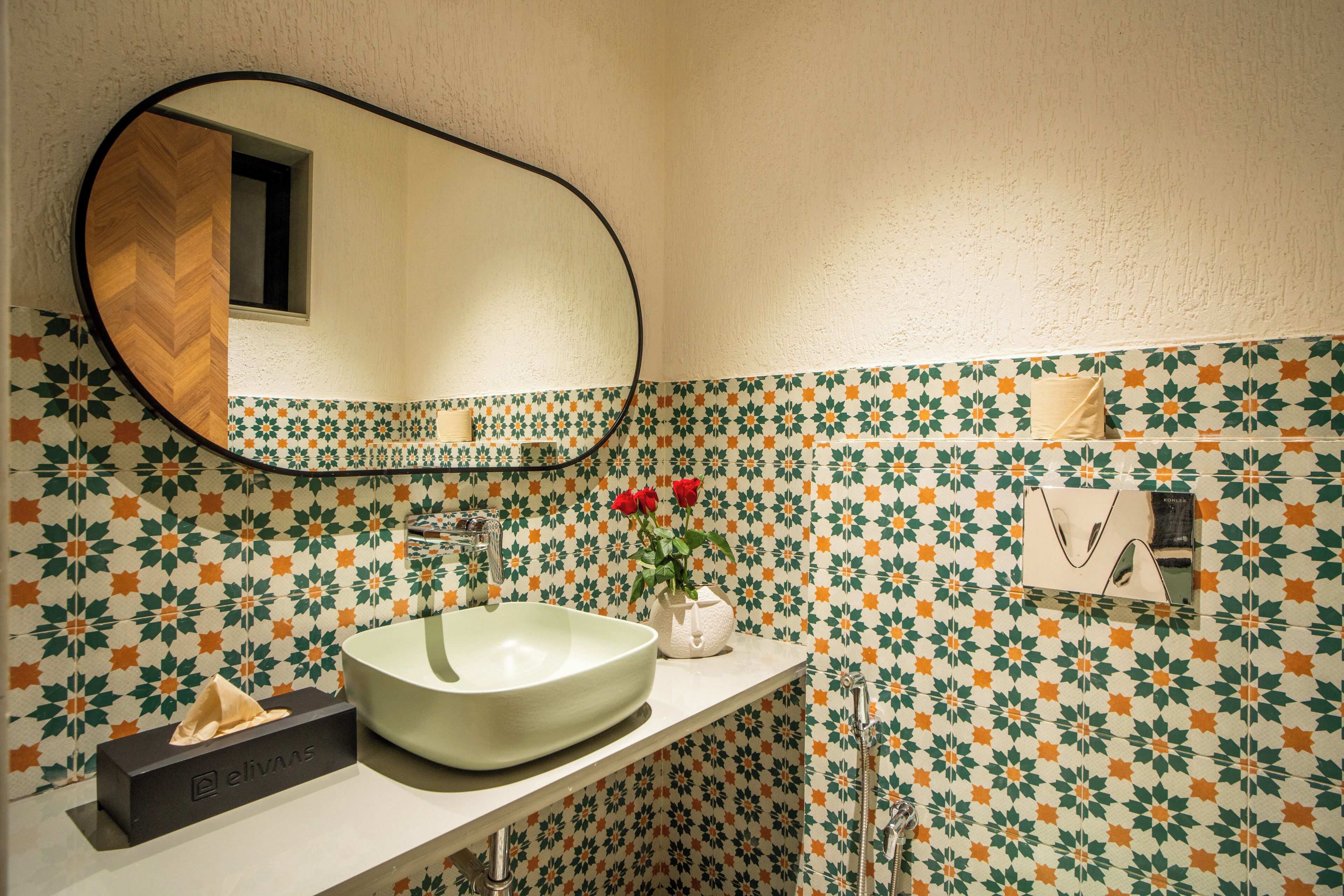 A bathroom with a large mirror, a vessel sink, and a patterned tile backsplash.