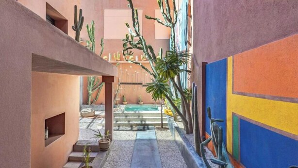 A narrow courtyard with a pool, cacti, and a colorful wall. - Villa Otia (Marrakech)