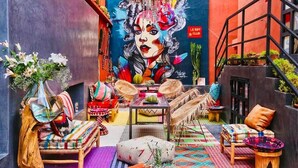 A vibrant interior with a mural, wicker furniture, and a staircase. - Villa Otia (Marrakech)