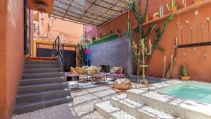 A pool area with a hot tub, steps leading to a covered patio, and cacti decorations. - Villa Otia (Marrakech)