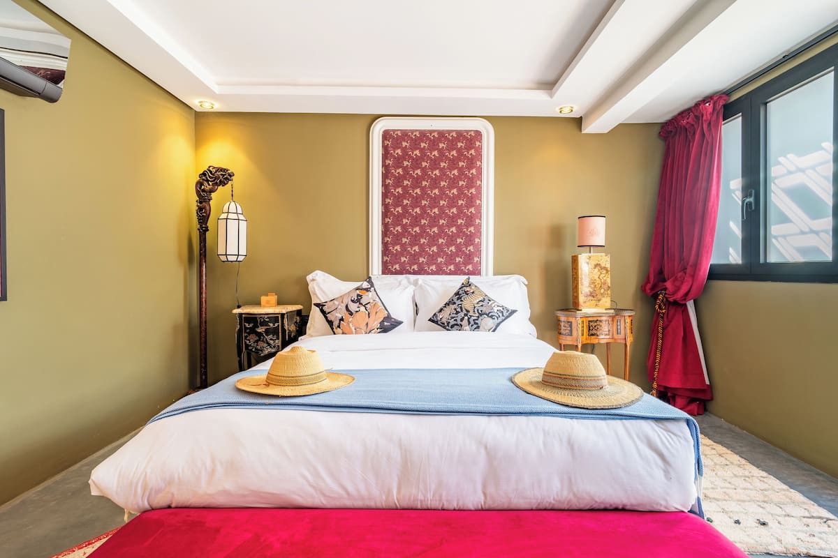 A hotel room with a large bed, a nightstand, a lamp, and a window with curtains.