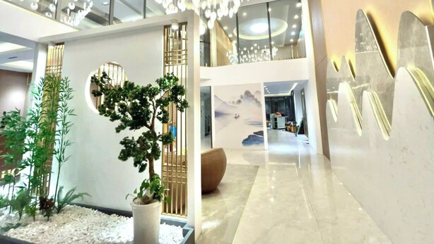 A modern lobby with a high ceiling, a large indoor plant, a seating area, and a mural on the wall. - AMY HOTEL (Kinh Bac)