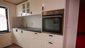 Una cocina con armarios blancos, encimera negra y horno de acero inoxidable.