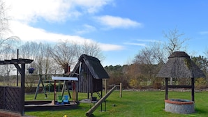 Un parque infantil con columpios, toboganes y una pequeña estructura de madera.