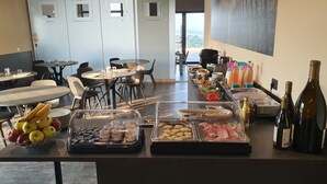 En buffet med forskellige retter og drikkevarer, herunder frugt, kød og flasker.