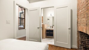 Een slaapkamer met een bed, een raam en een bakstenen muur.