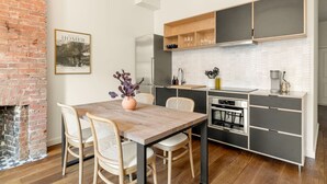 Een moderne keuken met een bakstenen muur, een houten eettafel en stoelen.