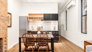 A modern kitchen with a dining area, featuring a brick wall, wooden flooring, and a built-in stove.