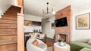 A modern living room with a fireplace, a dining area, and a staircase.