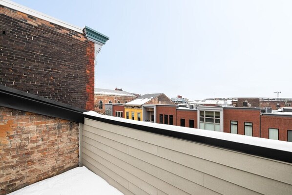 Un balcon avec un mur en briques et une vue sur les bâtiments voisins.