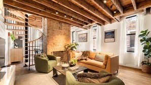 Un salon moderne avec un escalier, une cheminée et une grande fenêtre.