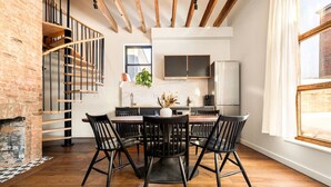 Une cuisine moderne avec un îlot central, un plancher en bois et un mur en briques.