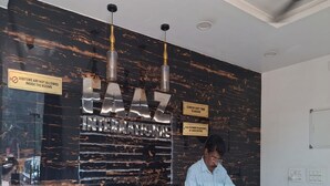 A hotel reception desk with a marble wall, a check-out time sign, and a QR code for digital check-in. - Hotel Faaz International (Kannur)