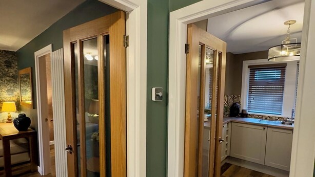 A hallway with wooden doors leading to a kitchen area. - Cochrane House (Stirling)