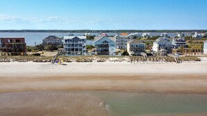 Une propriété située en bord de mer, comprenant plusieurs maisons, une plage de sable et une vue sur l’océan.